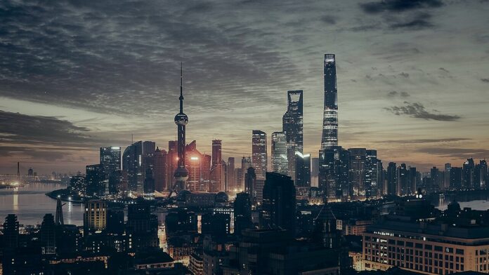 Shanghai skyline at dusk with the Oriental Pearl Tower and illuminated skyscrapers.
